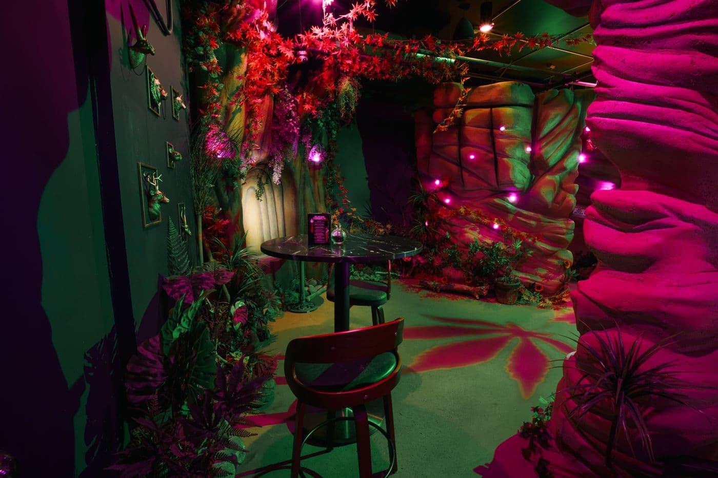 A high-top table in a green-lit nook between carved tree trunks