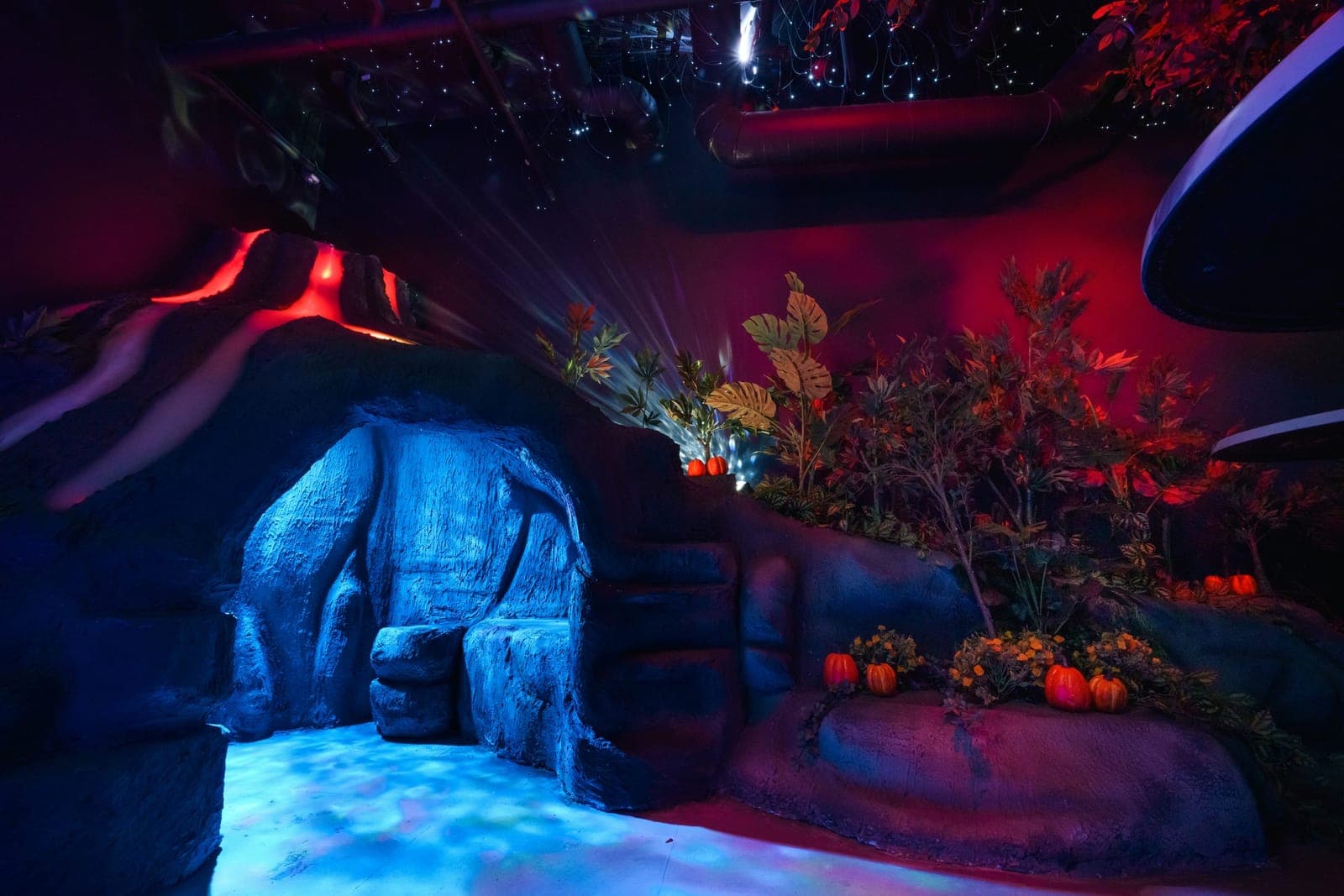 A blue-lit stone grotto with a carved seat, beside a flowering ledge