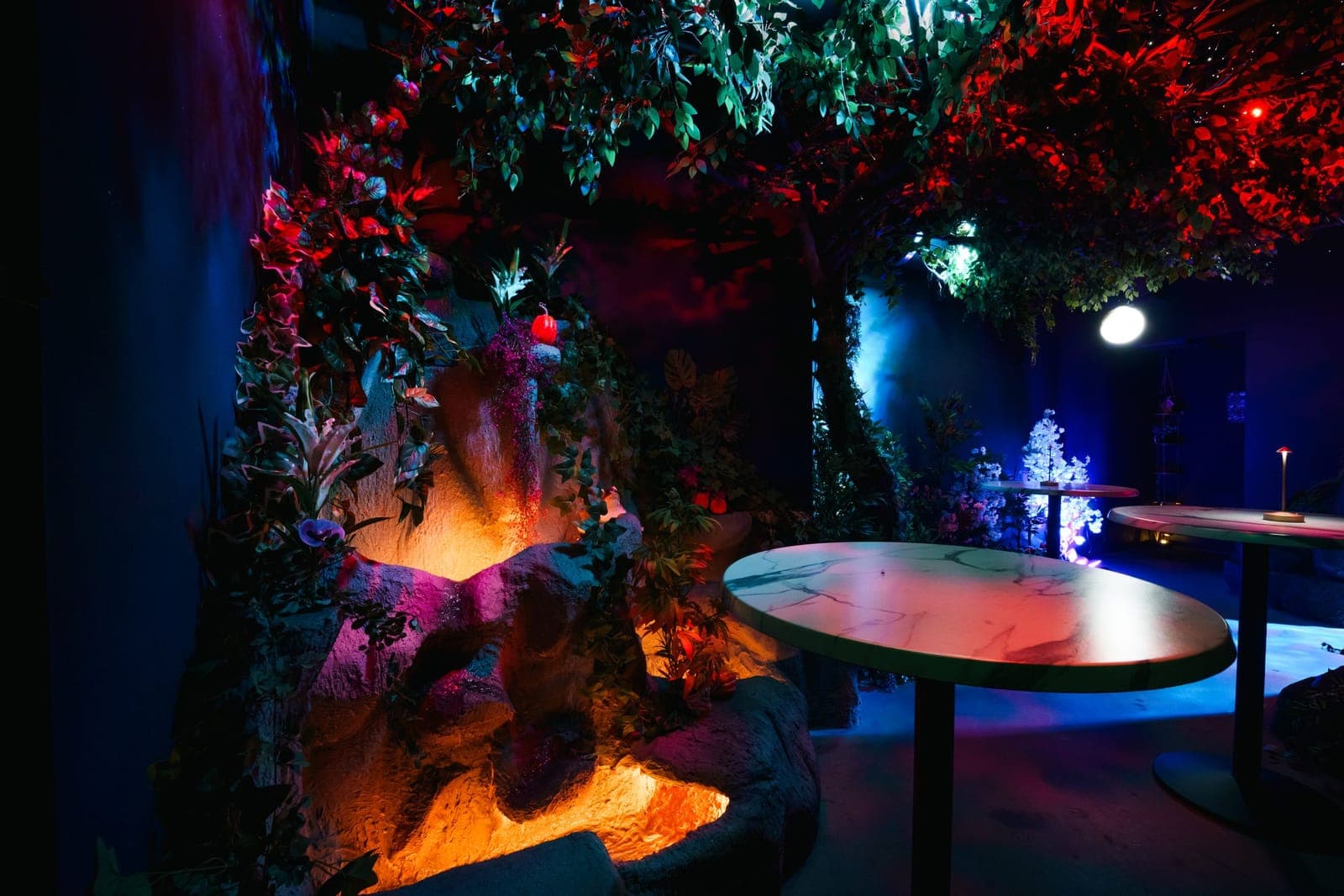 High-top tables beside a glowing orange volcano under red and green foliage